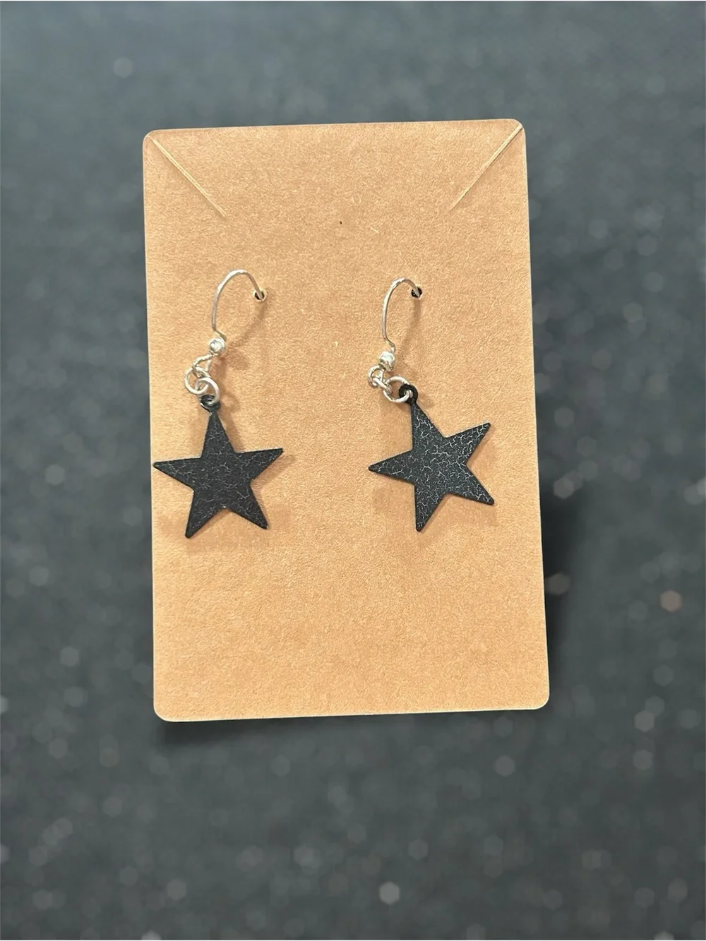 Kids black five point star dangle earrings featuring textured star charms